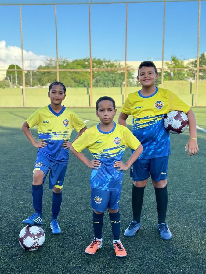 Três atletas da JW7 Academy com o uniforme amarelo e azul no campo